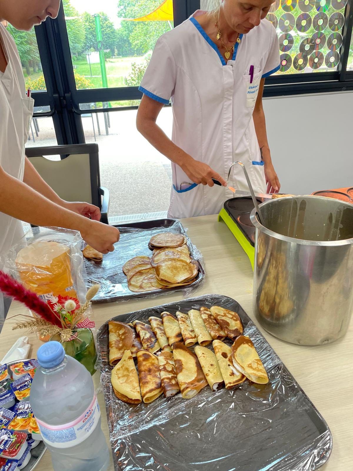 Des personnes disposent des pâtisseries cuites au four sur des plateaux recouverts de papier aluminium dans une cuisine ou un espace de préparation des aliments.