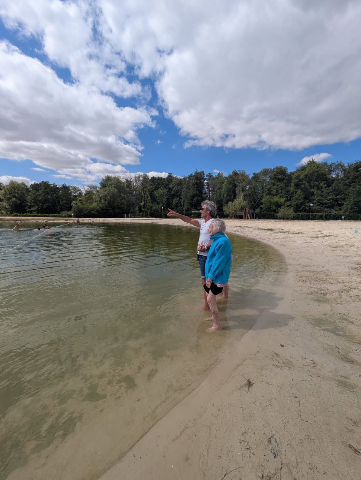 Personne debout dans l'eau peu profonde sur une plage de sable sous un ciel nuageux