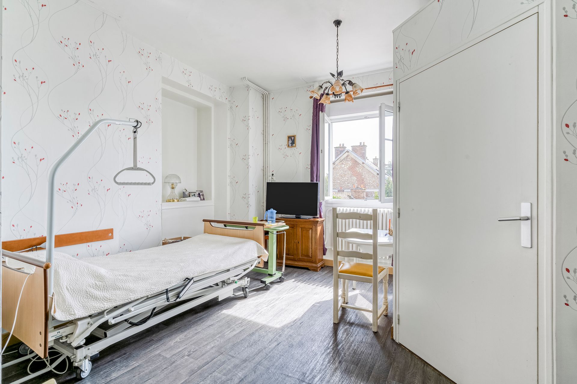 Chambre blanche lumineuse avec un lit, un bureau, une chaise et la lumière du soleil à la fenêtre