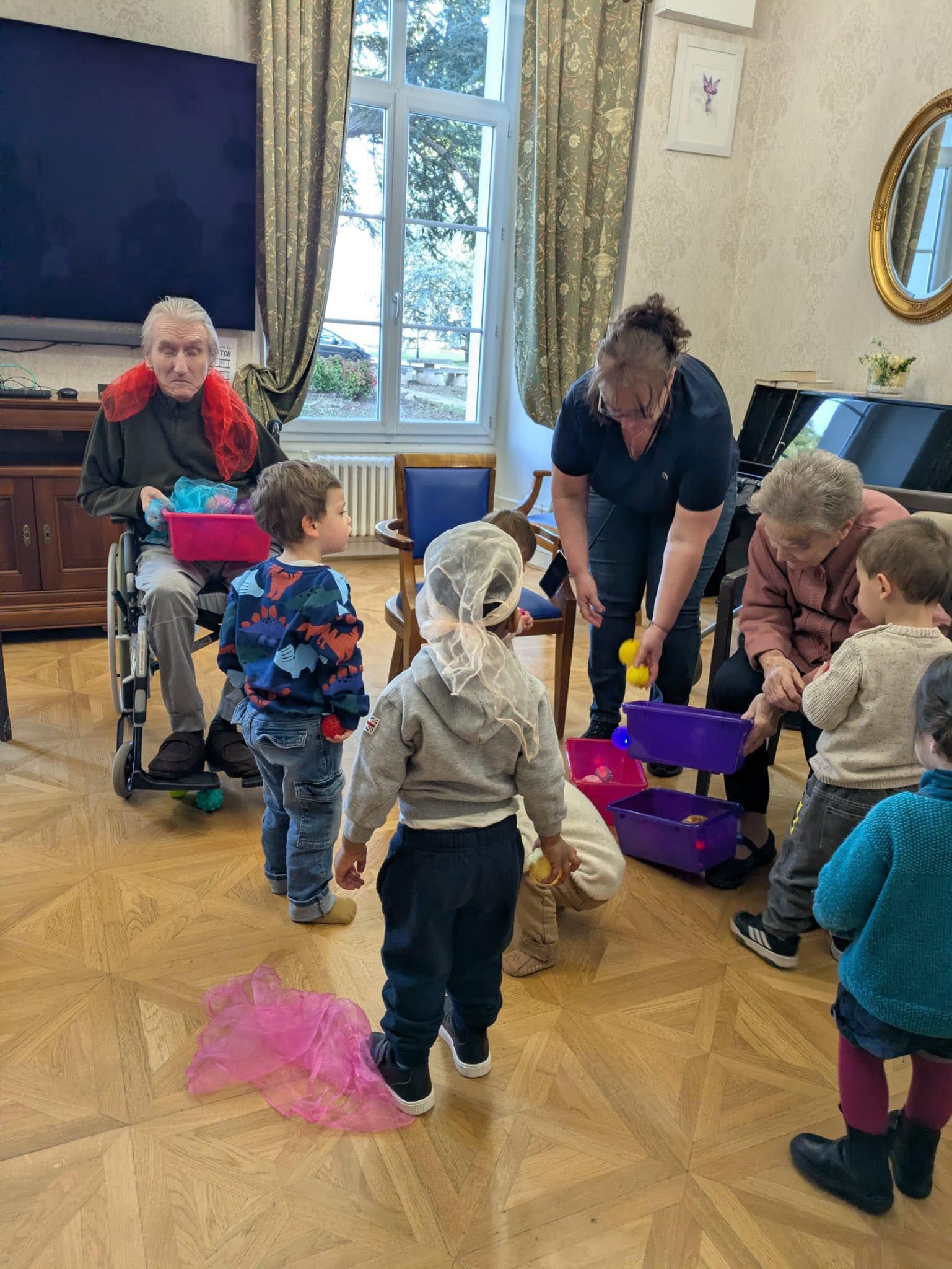 Des enfants étaient rassemblés autour d'un adulte dans une pièce, avec un jouet rose et violet posé sur le sol en bois.
