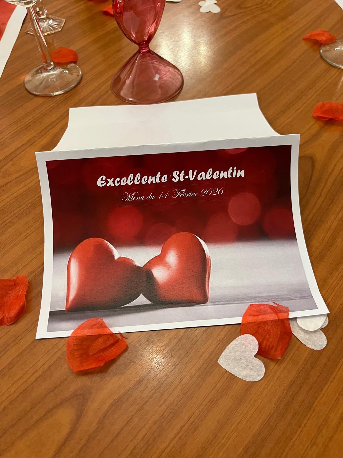 Carte de Saint-Valentin rouge posée sur une table en bois ornée de cœurs et de pétales rouges et blancs éparpillés.