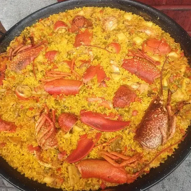 Una sartén llena de arroz, langostas y verduras.