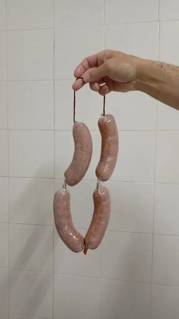 Una persona sostiene una tira de salchichas en su mano.