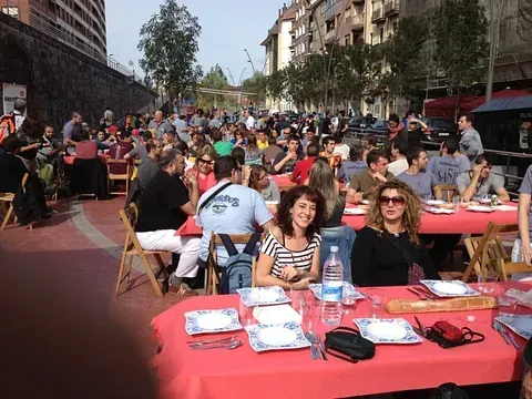 Un grupo grande de personas están sentadas en mesas afuera.