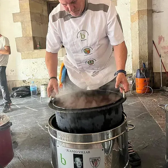 Un hombre está cocinando en una olla con la letra b en ella.