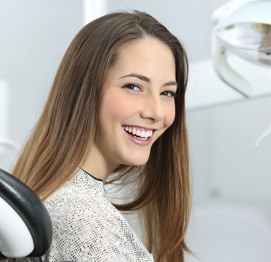Una mujer sonríe mientras está sentada en una silla dental.