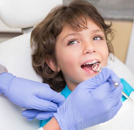 Un niño pequeño se está haciendo examinar los dientes por un dentista.