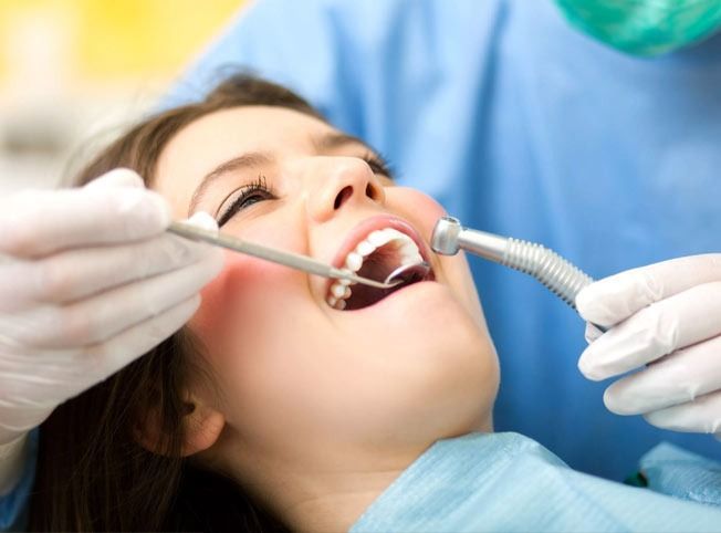 Una mujer se está haciendo examinar los dientes por un dentista.
