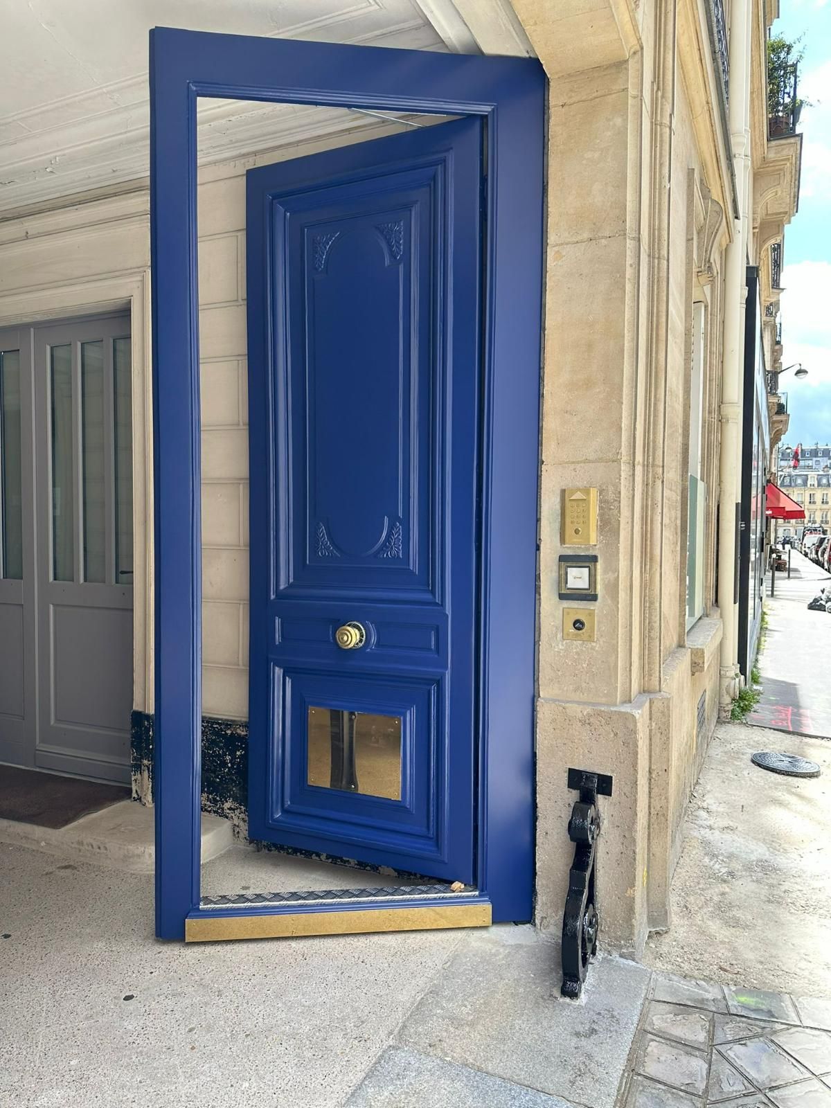 Une porte d'un bleu éclatant, entrouverte dans un encadrement en pierre, laisse entrevoir l'intérieur.
