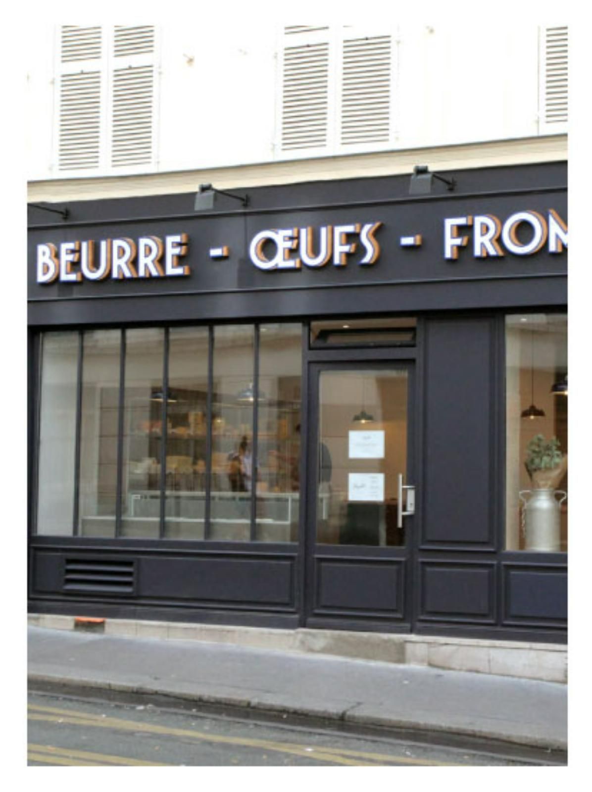 Façade de magasin avec l'enseigne « BEURRE - ŒUFS - FROMAGE » en lettres blanches sur une façade noire.