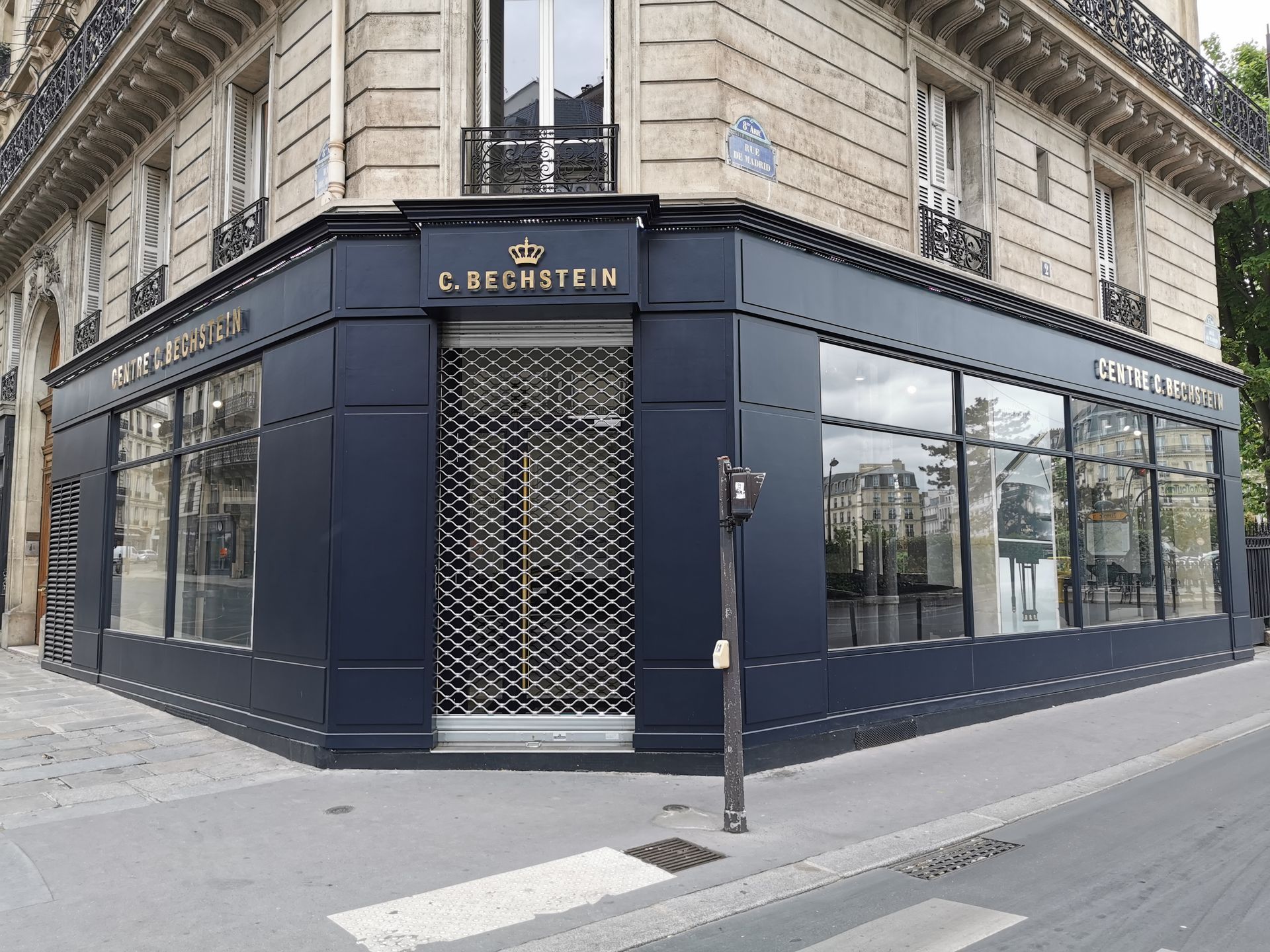 Une devanture d'angle bleu foncé avec l'inscription dorée « C. Bechstein » et un portail de sécurité métallique fermé à Paris.