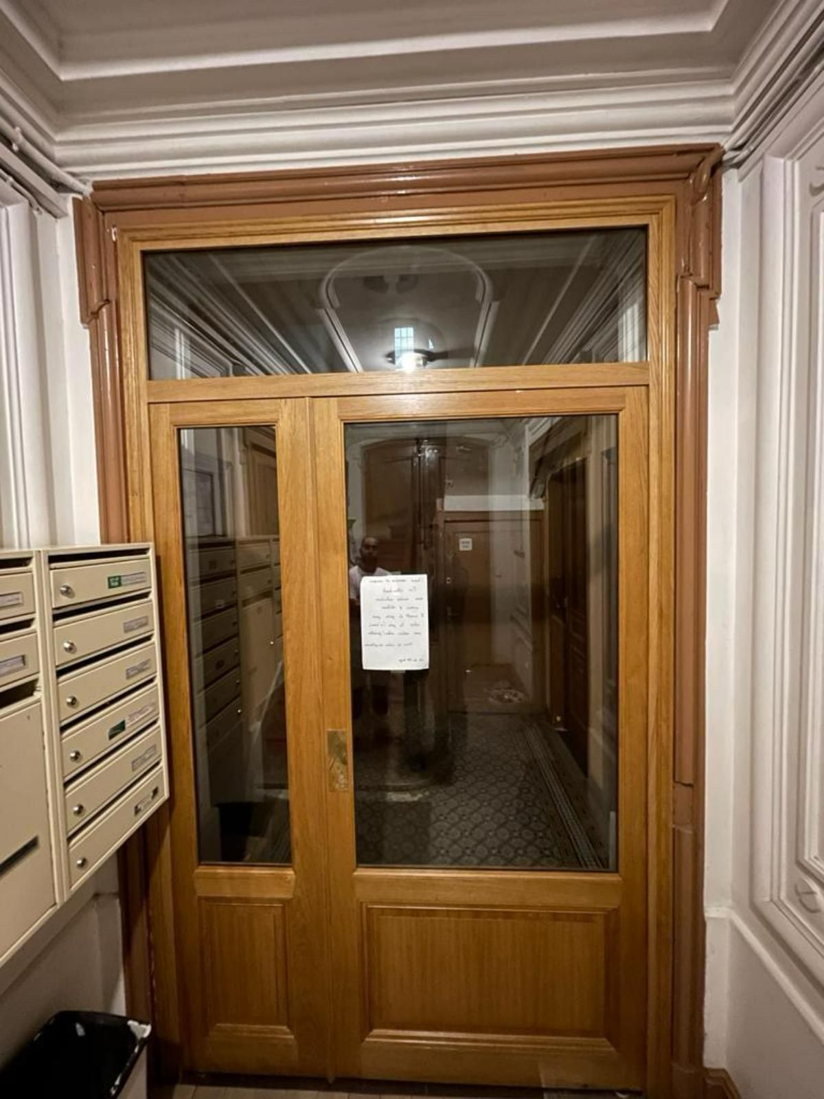 Porte d'entrée en bois avec panneaux de verre ; boîtes aux lettres à gauche.