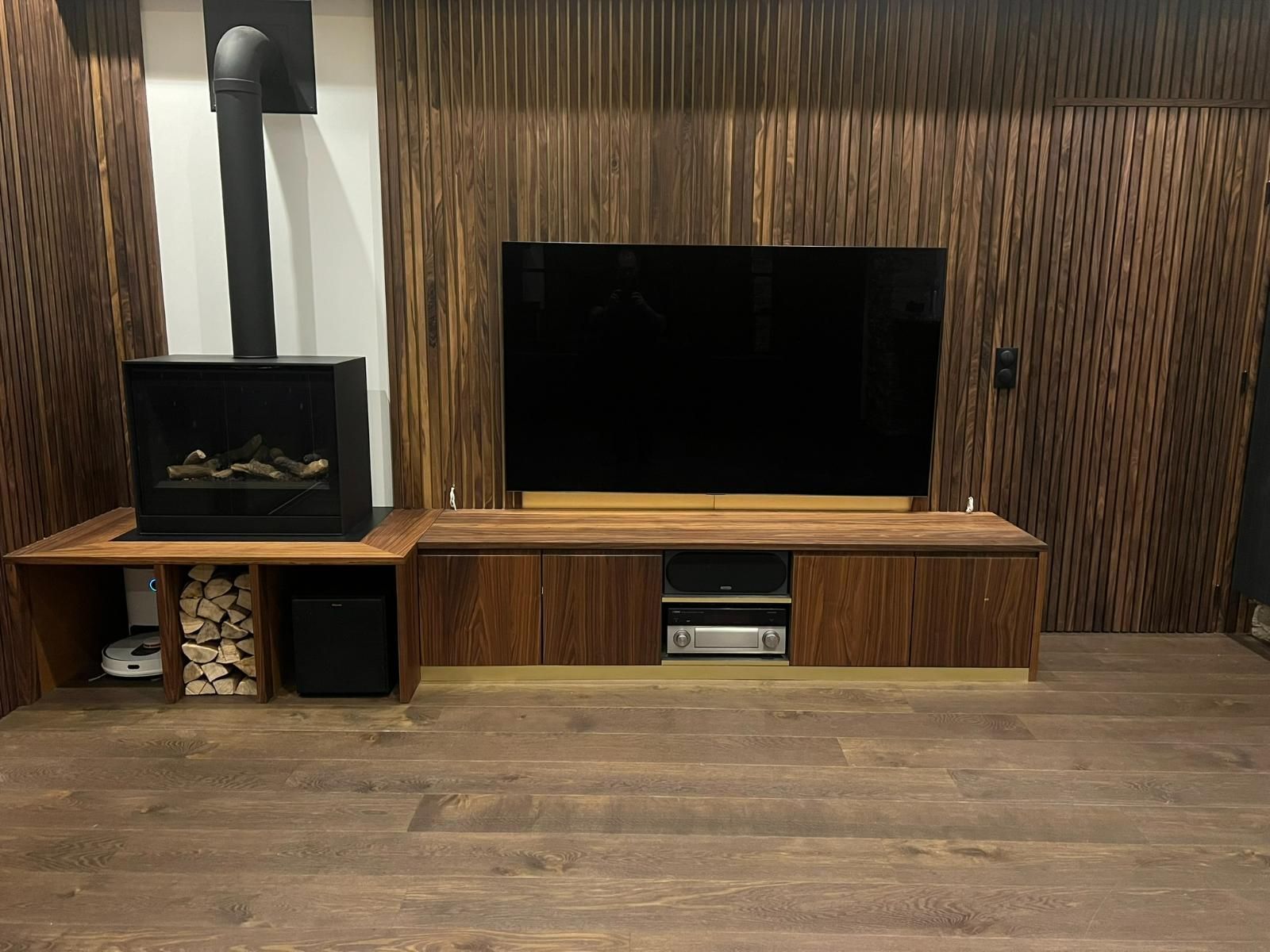 Meuble TV en bois avec télévision, cheminée et rangements intégrés dans un salon moderne.