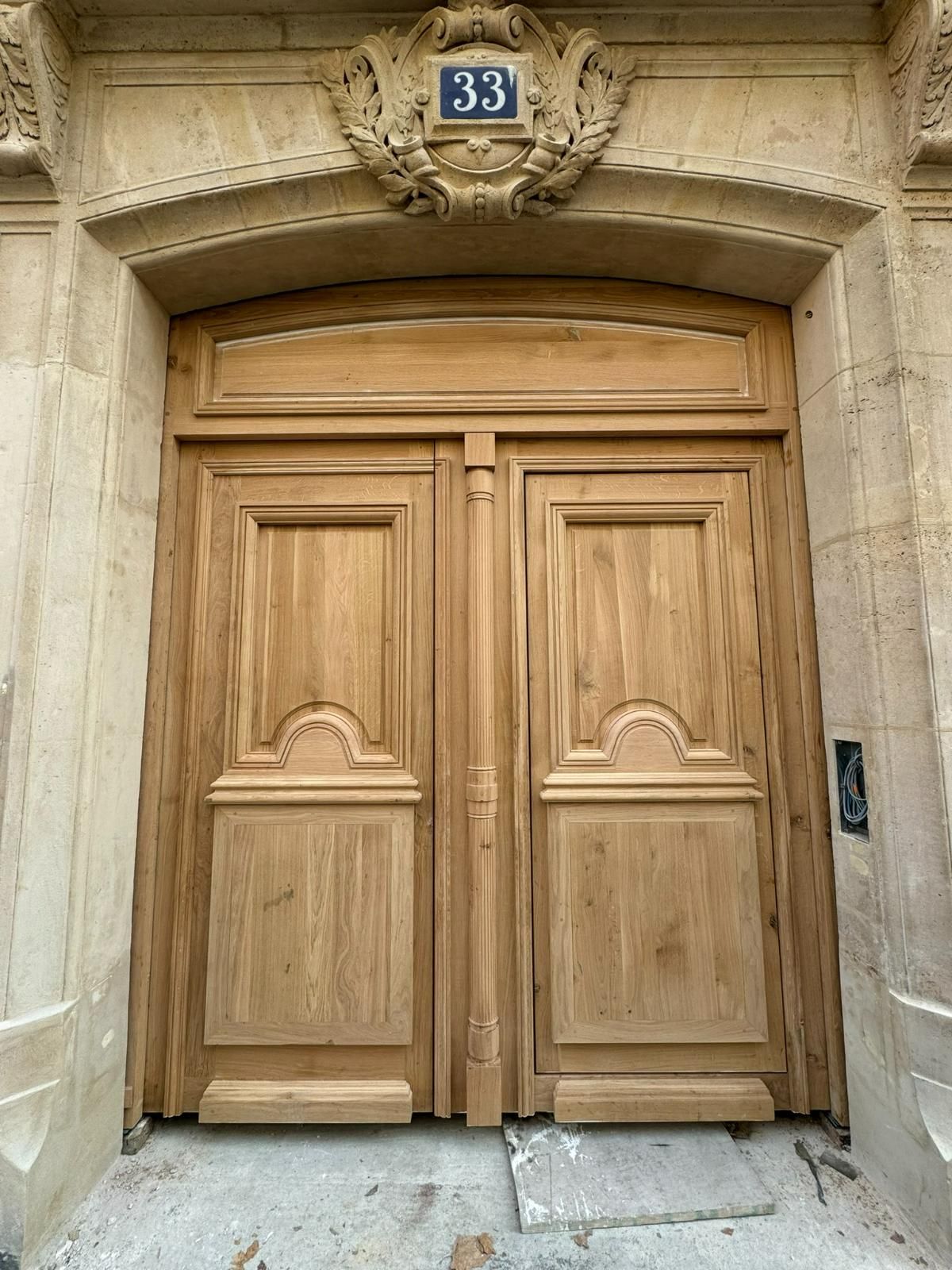 Double porte en bois avec le numéro 33 au-dessus, encastrée dans une façade en pierre.