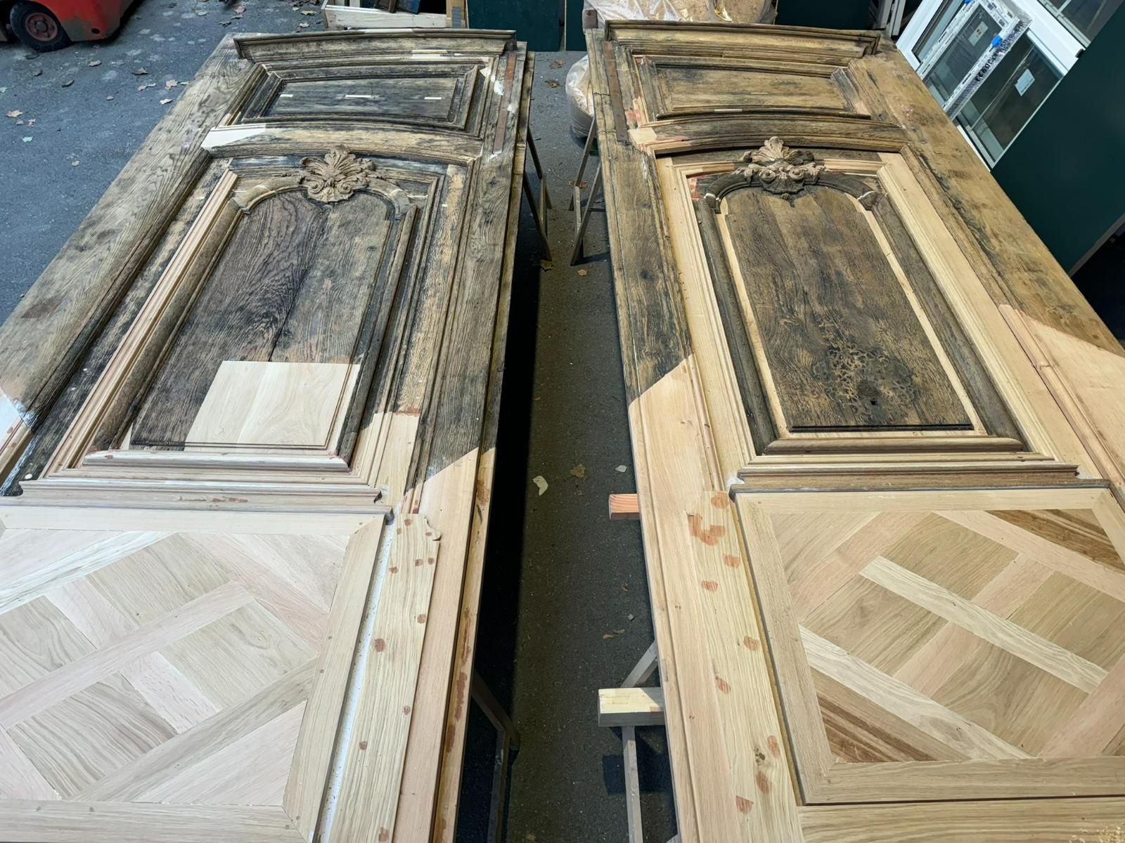 Deux portes en bois finement sculptées et un panneau inférieur de style parquet, dans un atelier.