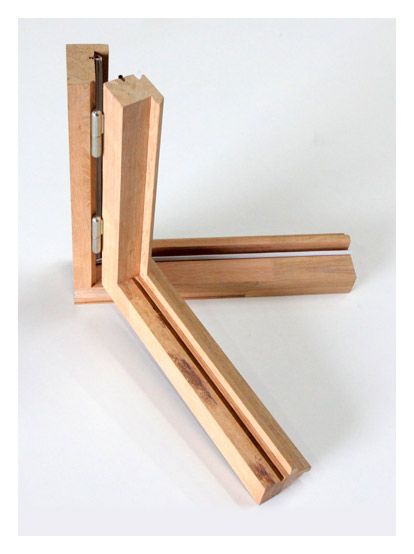 Échantillons de cadres d'angle en bois reliés par une charnière métallique sur fond blanc.