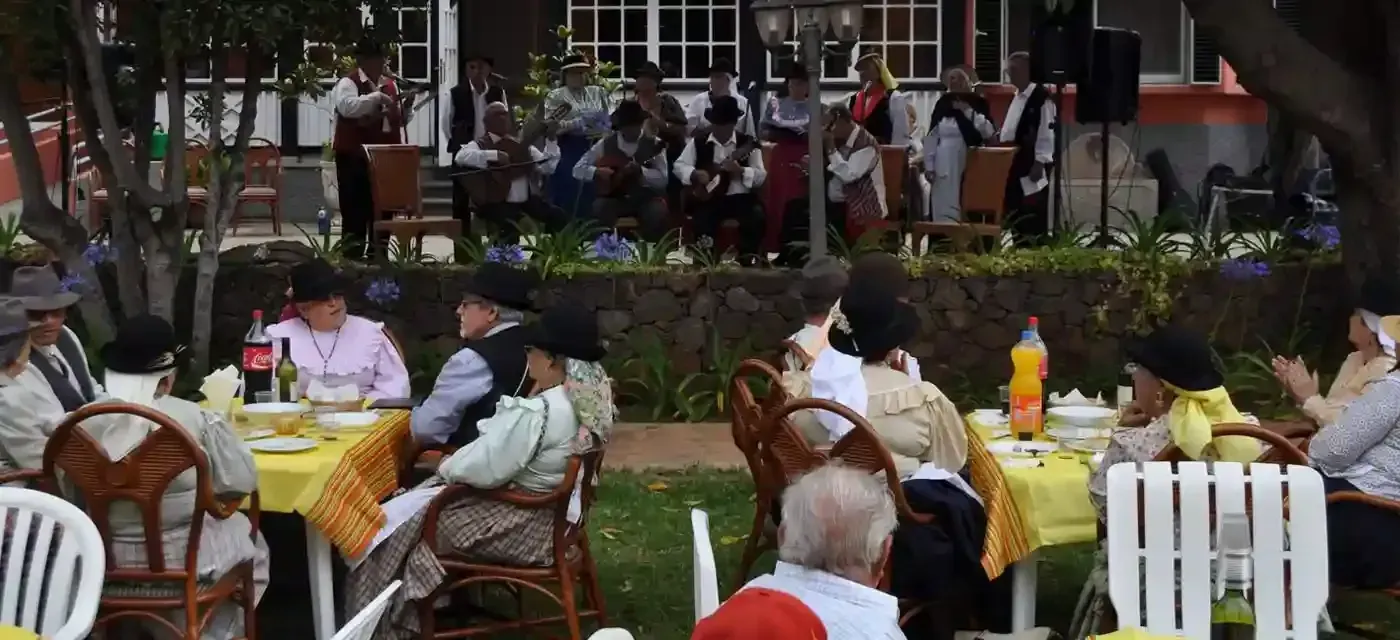 Un grupo de personas están sentadas en mesas en un parque.