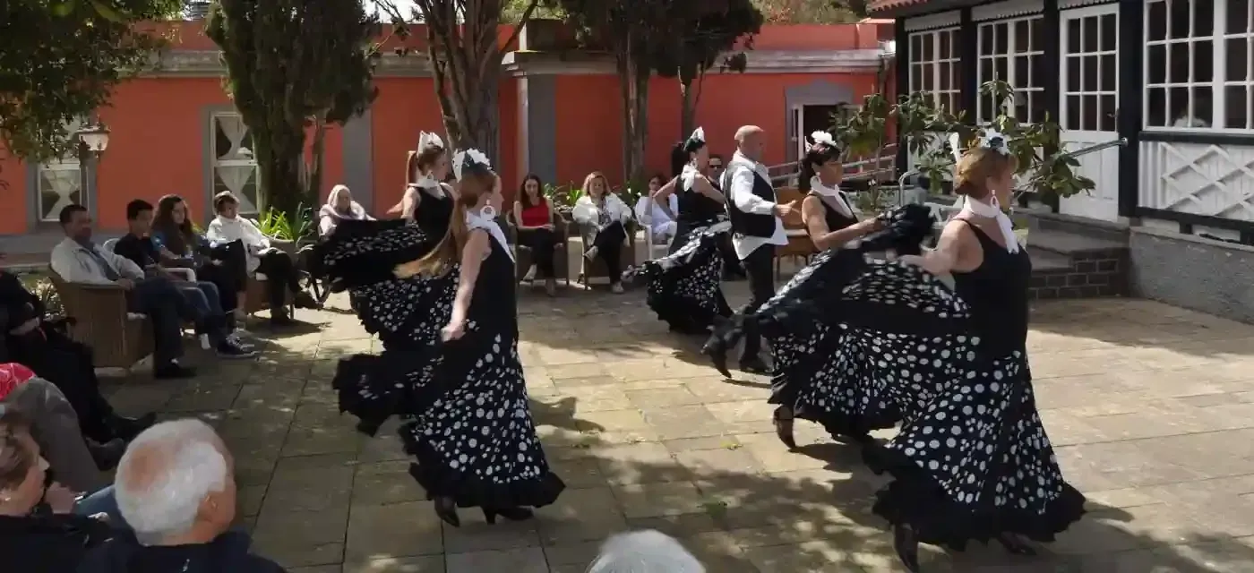 Un grupo de personas está bailando en un patio frente a un edificio.