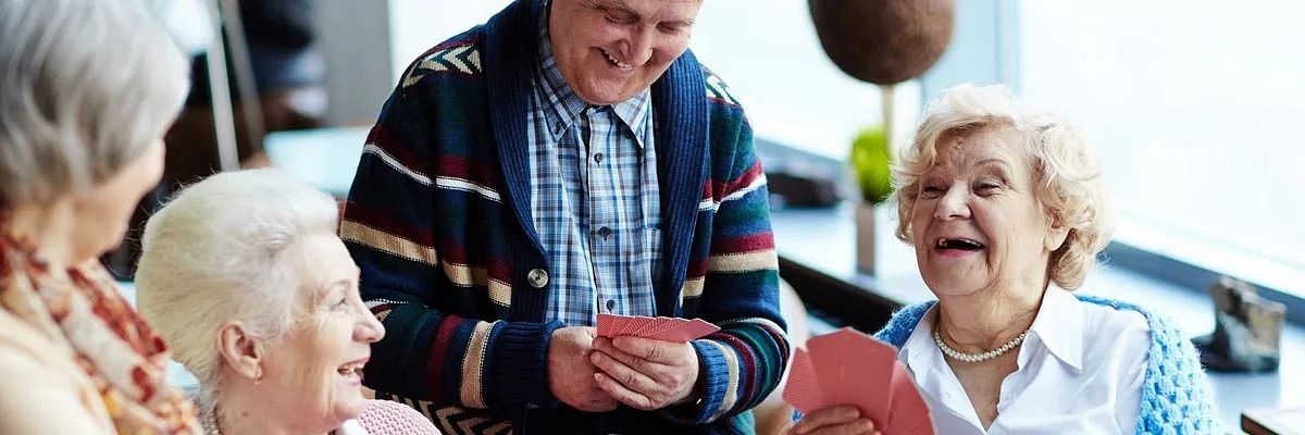 Un grupo de personas mayores están jugando a las cartas juntos.