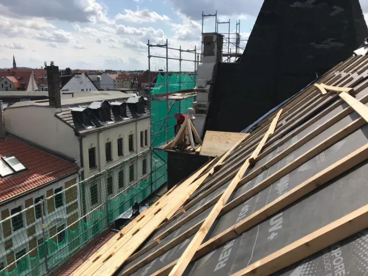 Zimmerei Andreas Karl GmbH - Gebäudedach in einer Innenstadt, Baugerüst mit grünem Fangnetz