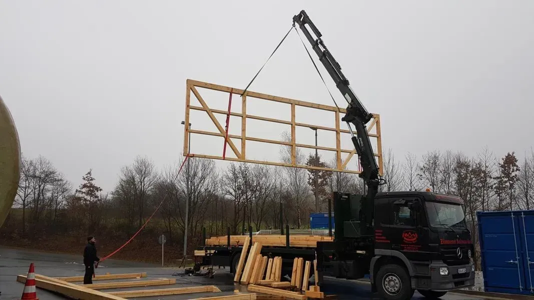 Zimmerei Andreas Karl GmbH - Holzgerüst einer Hauswand wird mit Kran von LKW entladen
