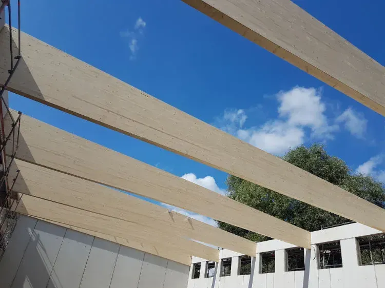 Zimmerei Andreas Karl GmbH - Querbalken aus Holz formen das Gerüst eines Schrägdaches, blauer Himmel im Hintergrund