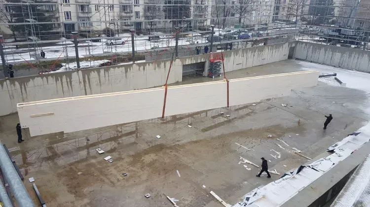 Zimmerei Andreas Karl GmbH - Langes Bauteil aus Holz hängt am Kranseil über einer Baustelle