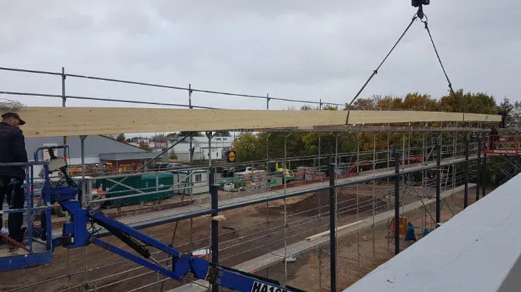 Zimmerei Andreas Karl GmbH - Sehr langes Holzbauteil wird mit Kran über Baustelle gehoben