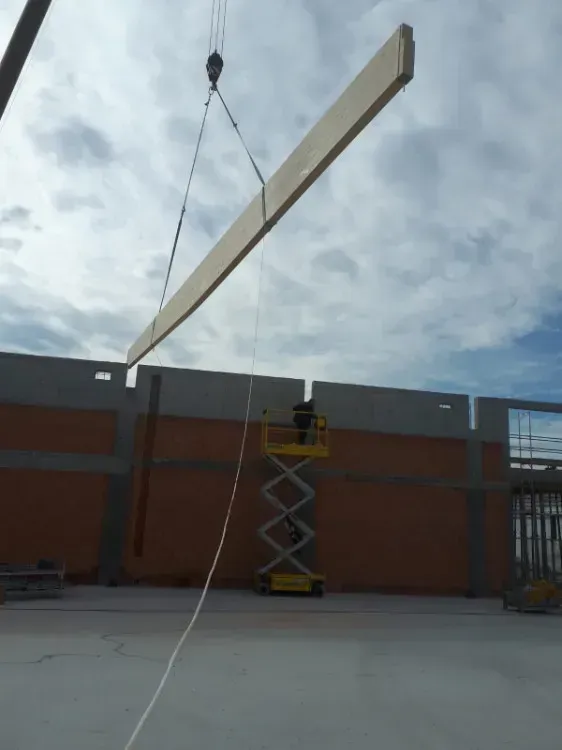 Zimmerei Andreas Karl GmbH - Holzbalken wird mit Kran in Fuge an einer Gebäudewand eingelassen