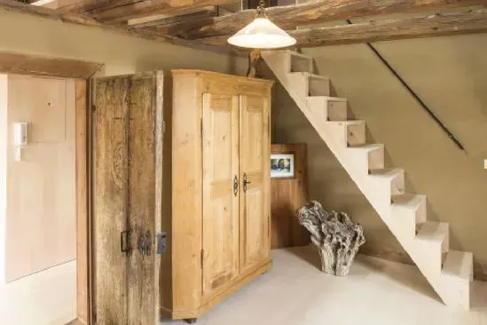 Zimmerei Andreas Karl GmbH - alter Holzschrank in einem kargen Raum mit Treppe