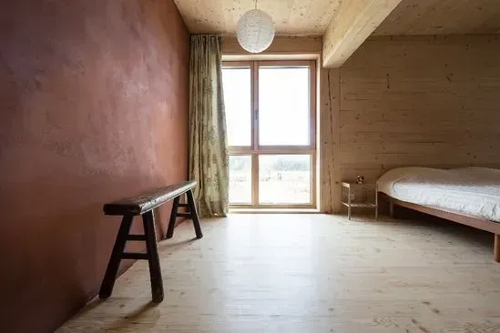 Zimmerei Andreas Karl GmbH - geräumiges Schlafzimmer mit Holzboden, Holzwand und großem Fenster