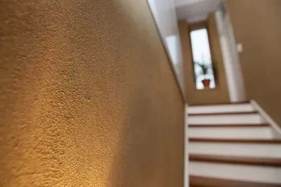 Zimmerei Andreas Karl GmbH - Nahaufnahme einer braunen Wand mit Treppe im Hintergrund