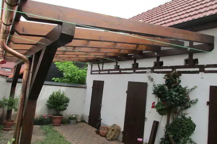 Zimmerei Andreas Karl GmbH - Vordach aus Holzbalken mit Regenrinne an einem Wohnhaus