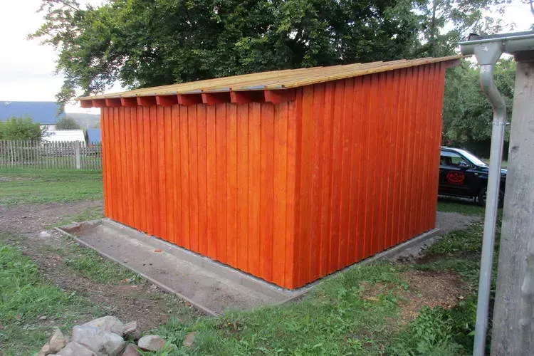 Zimmerei Andreas Karl GmbH - Gartenschuppen aus orangerotem Holz von hinten betrachtet