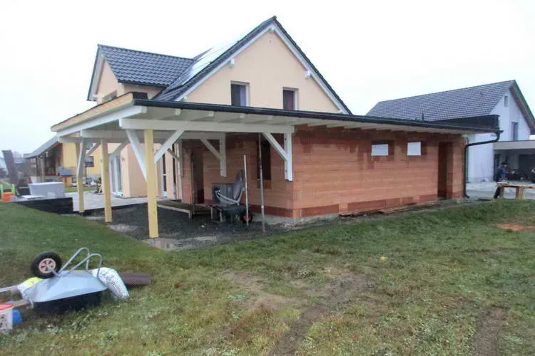 Zimmerei Andreas Karl GmbH - Haus mit Vordach aus Holz, grüne Wiese