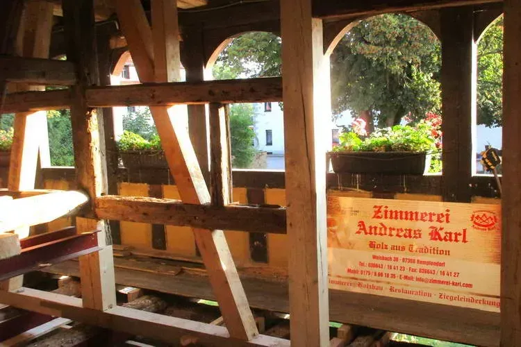 Zimmerei Andreas Karl GmbH - Holzkonstruktion im Sonnenlicht, Firmenlogo an Wand