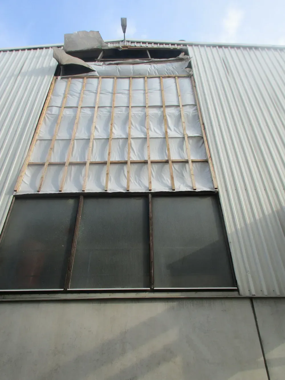 Zimmerei Andreas Karl GmbH - Holzbalken hinter einer Wellblech-Gebäudefassade