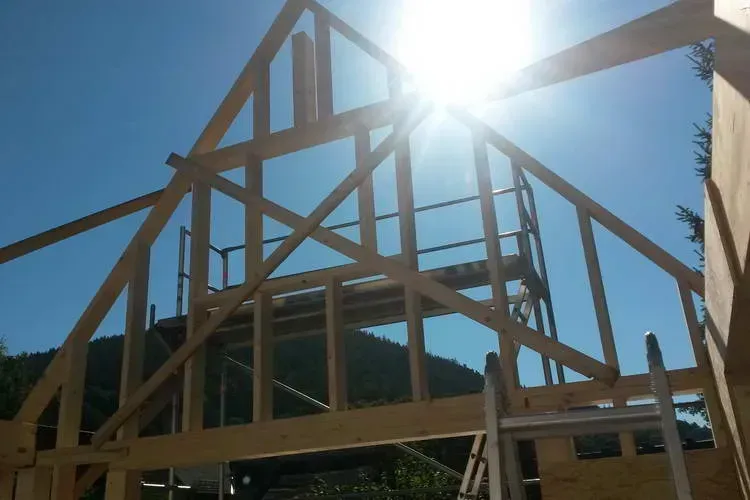 Zimmerei Andreas Karl GmbH - Holzkonstruktion in Dreiecksform für ein Dachgeschoss, blauer Himmel im Hintergrund