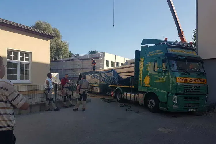 Zimmerei Andreas Karl GmbH - drei Arbeiter neben einem grünen Transport-LKW mit Holzbauteilen