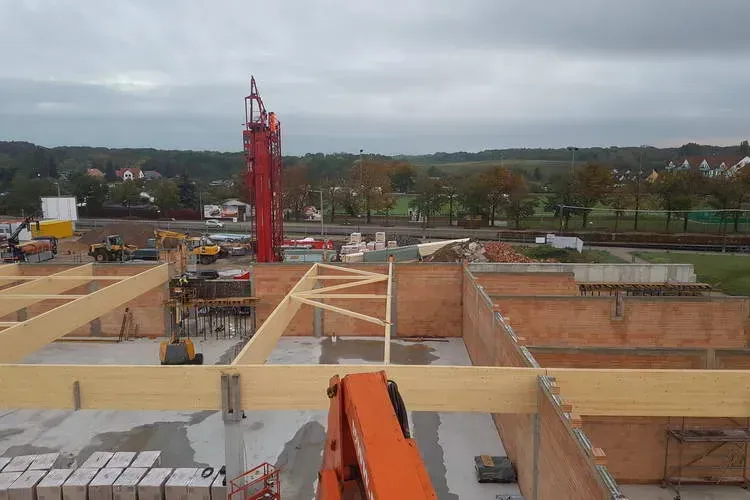 Zimmerei Andreas Karl GmbH - Panoramasicht einer Baustelle, Baukran, Holzbalken und Steinwände