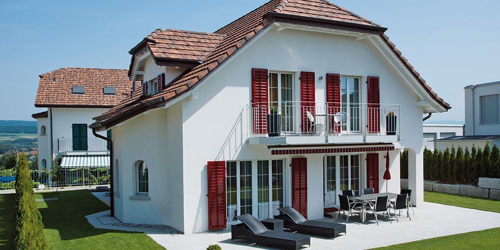 Una casa bianca con le persiane rosse alle finestre