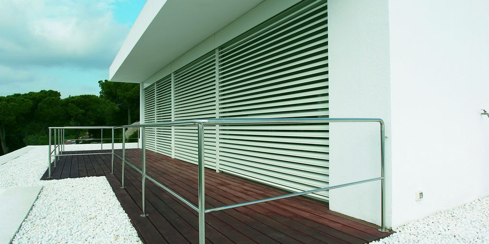 Una casa bianca con un ponte di legno e una ringhiera di metallo