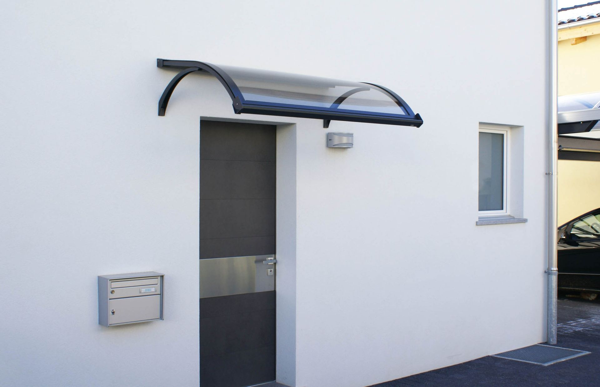 Un edificio bianco con una porta nera e una tettoia sopra