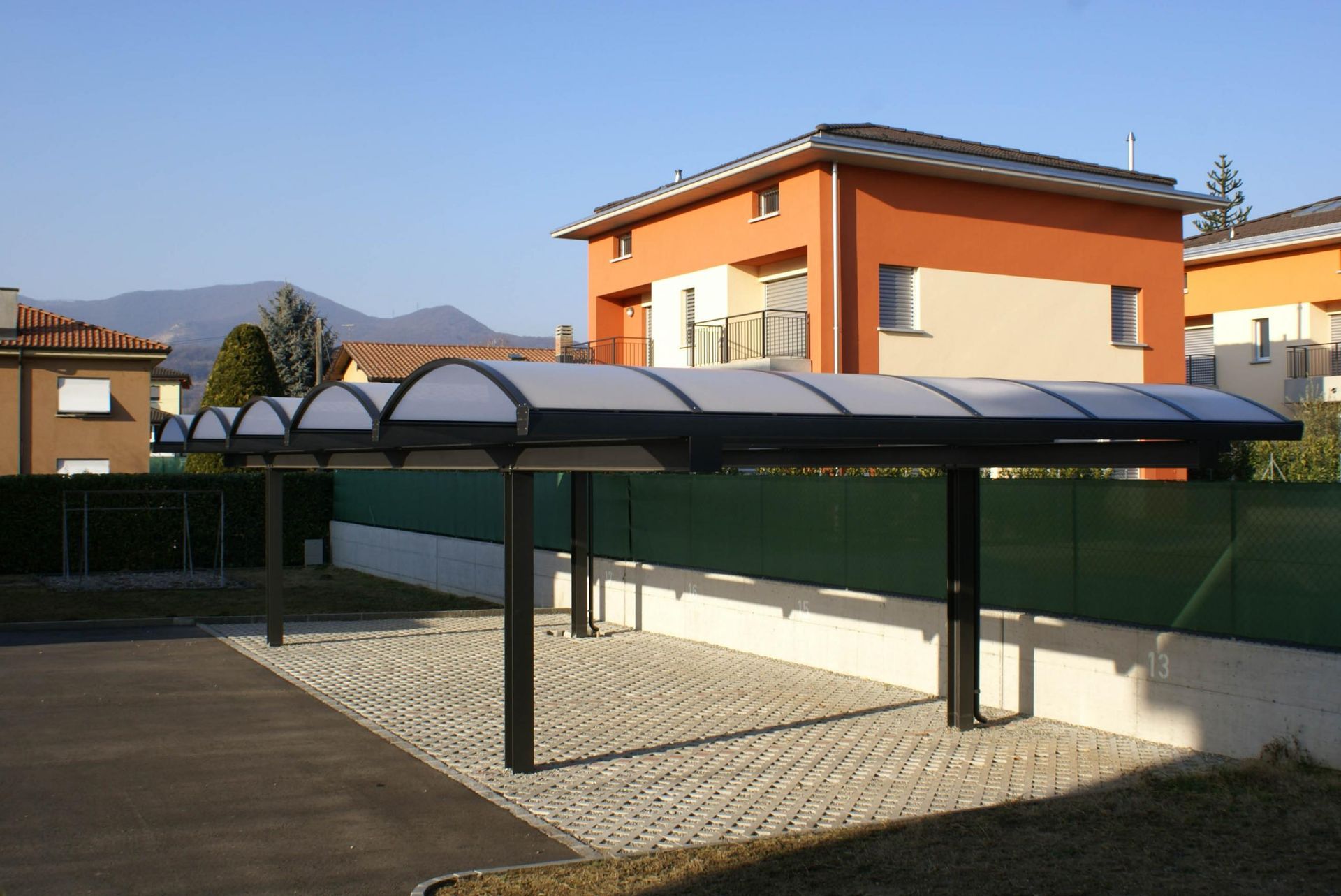 Un posto auto coperto davanti a una casa con una recinzione verde