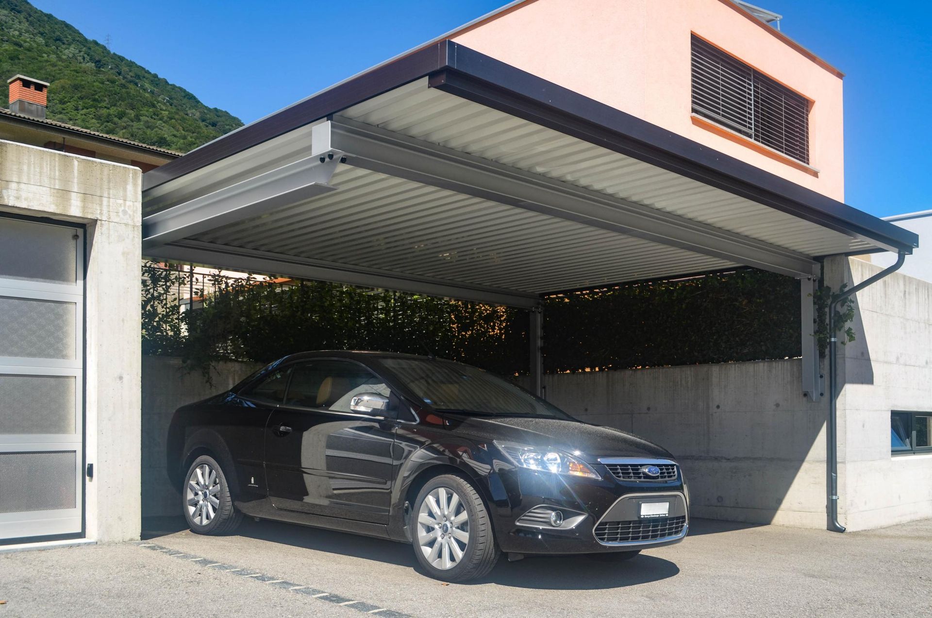 Un'auto è parcheggiata sotto una tettoia davanti a una casa