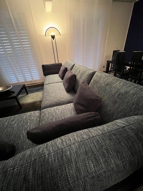 Un soggiorno con un divano grigio e cuscini viola.