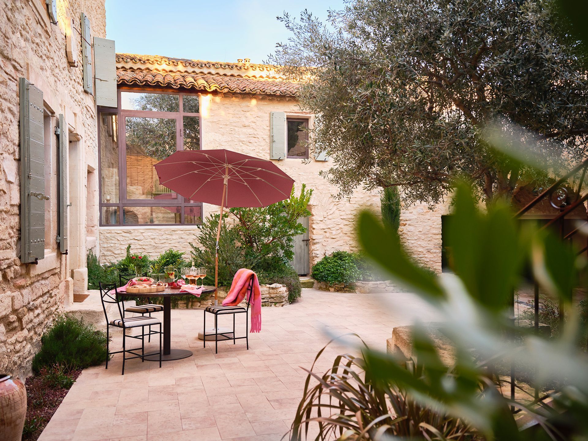 Un patio con tavolo, sedie e un ombrellone di fronte a un edificio in pietra.