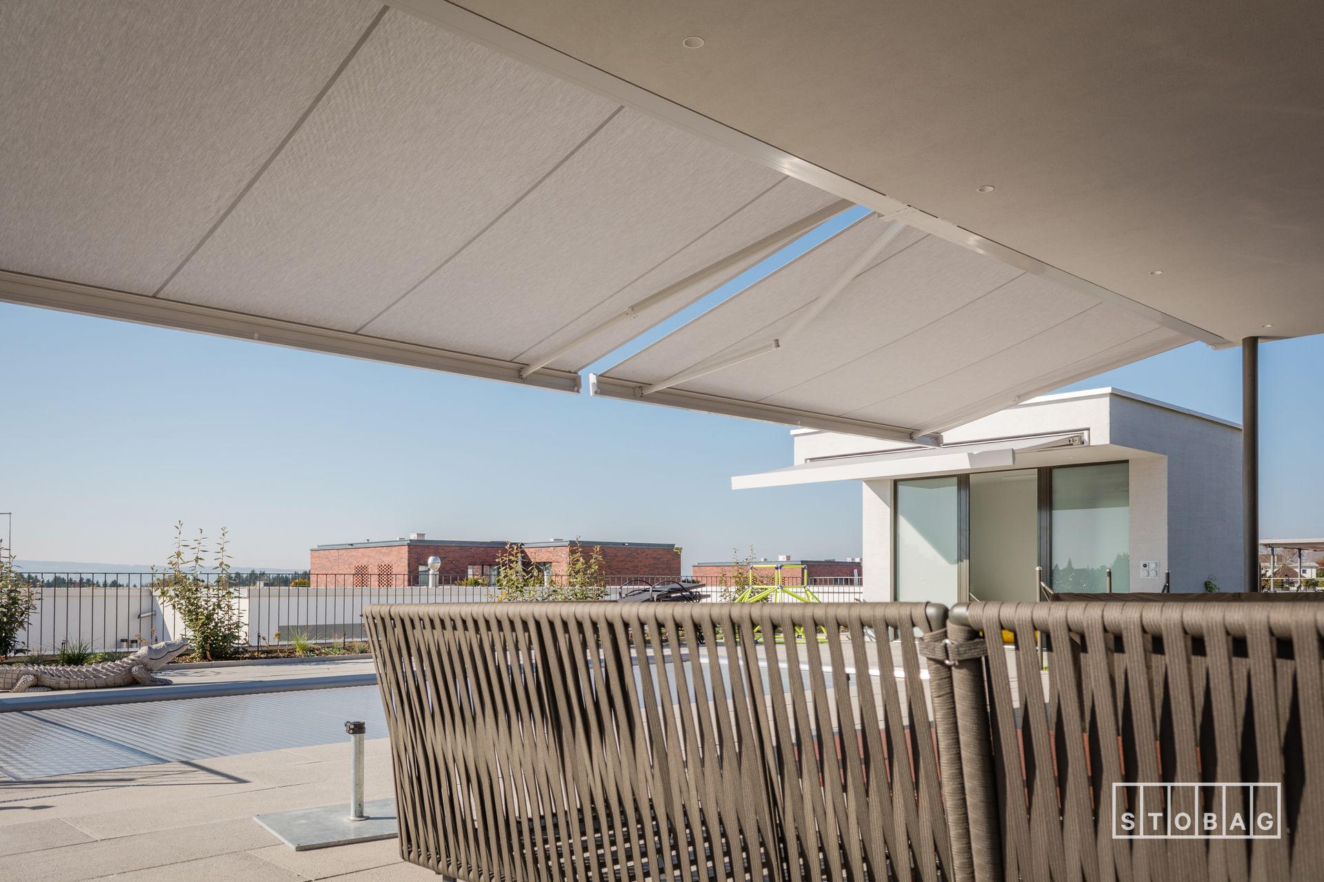 Una tenda da sole bianca è appesa sopra una recinzione vicino a una piscina.