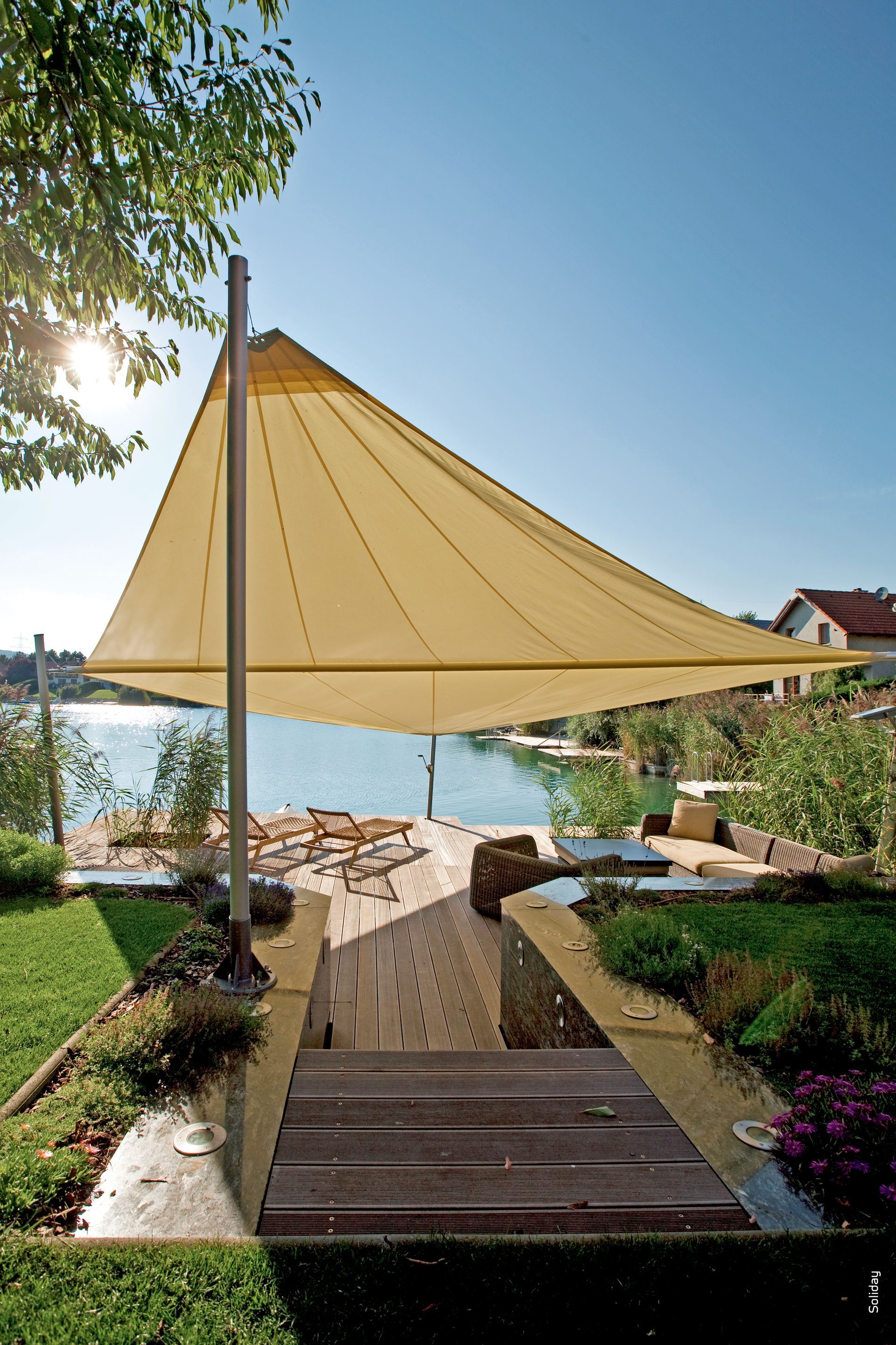 Un grande ombrellone è posizionato in cima a una terrazza di legno che domina uno specchio d'acqua.
