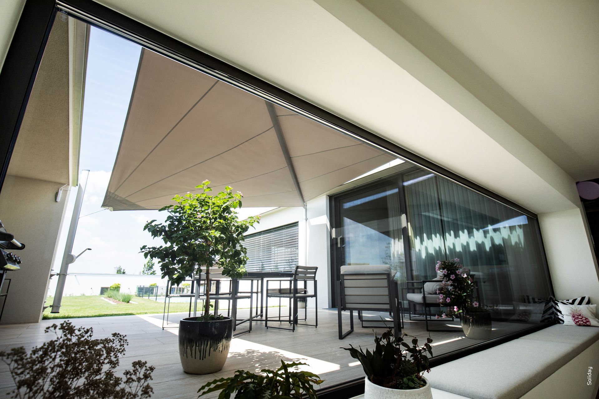 Una grande finestra con vista su un patio con tavolo e sedie